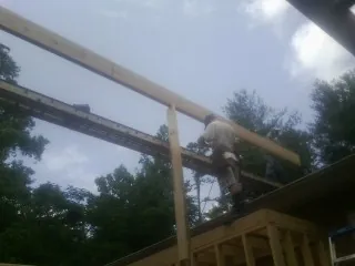 Carpenter setting a ridge beam over a new addition frame — Ice Dam Removal by Roofing Brothers in Tenafly
