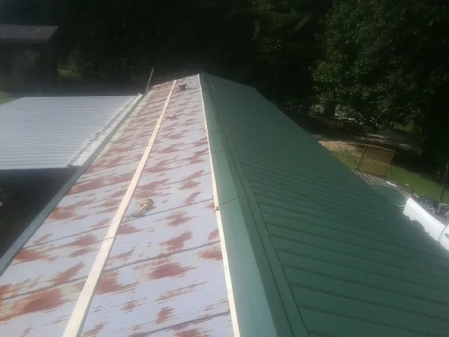 Old rusted panels beside newly installed green metal roofing — Wind Damage Roof Repair by Roofing Brothers in Tenafly