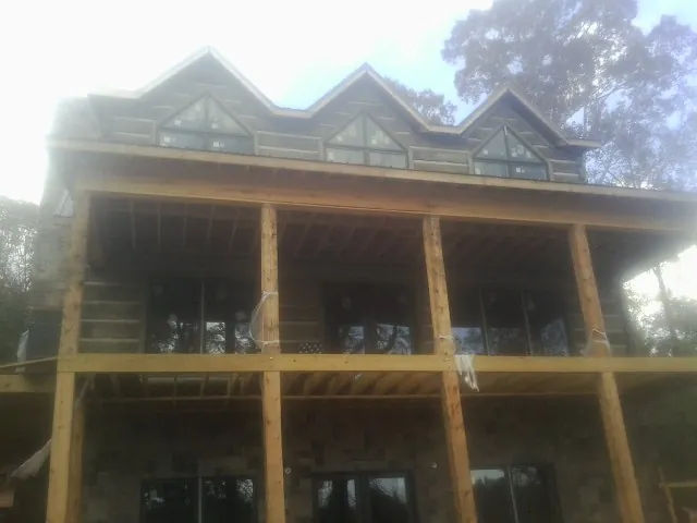 Dormers and porch framing on a large log home under construction — Roof Coating work by our crew in Tenafly