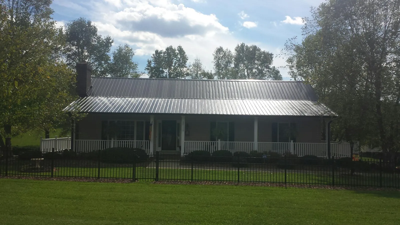 Gray metal roof on a brick ranch with a full width front porch — Gutter Guard Installation work by our crew in Tenafly