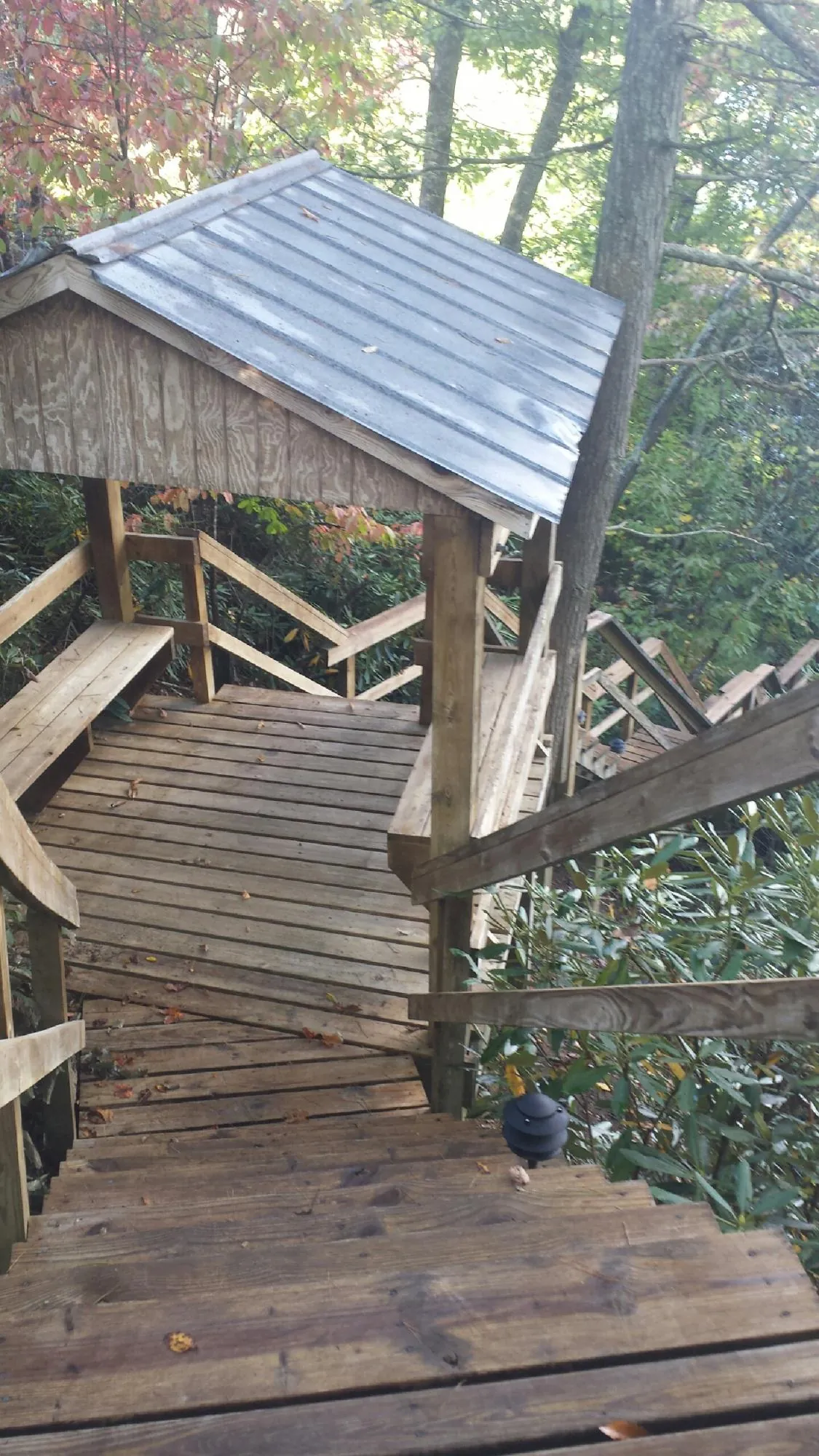 Metal roofed shelter over wooden steps on a wooded walkway — Skylight Repair & Installation work by our crew in Tenafly