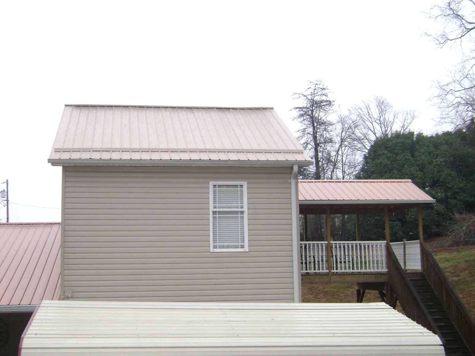 Tan metal roofs on a two story addition and attached porch, from a Roof Replacement job in Tenafly