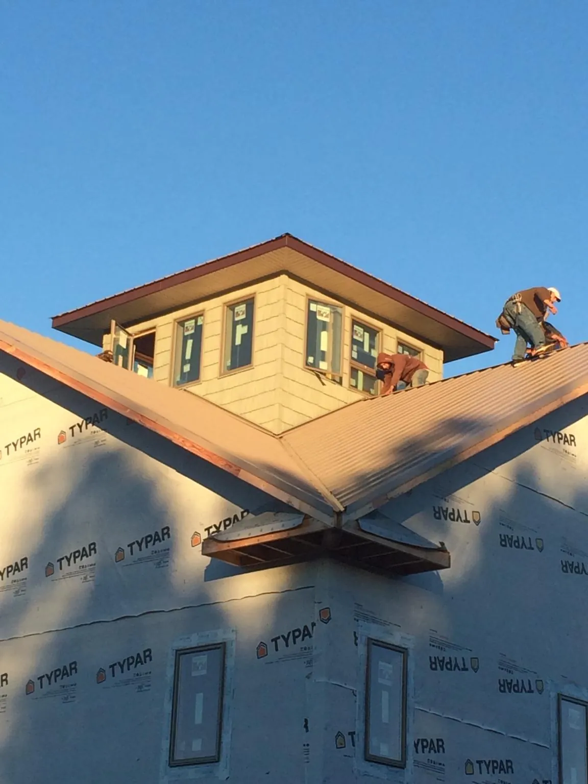 Roofers working around a rooftop cupola on a new metal roof at sunset — Roof Waterproofing in Tenafly by Roofing Brothers